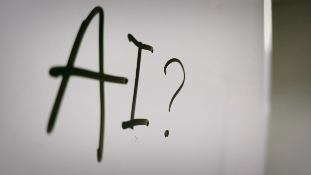The letters AI and a question mark written on a whiteboard